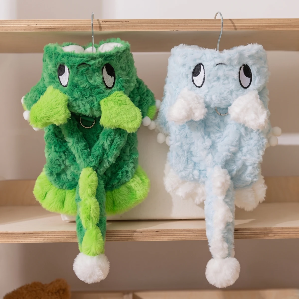 TruePet Dino-Kostüm in Grün und Blau auf Kleiderbügeln, Plüsch mit Rückenzacken, Ärmchen und Bommel-Schwanz