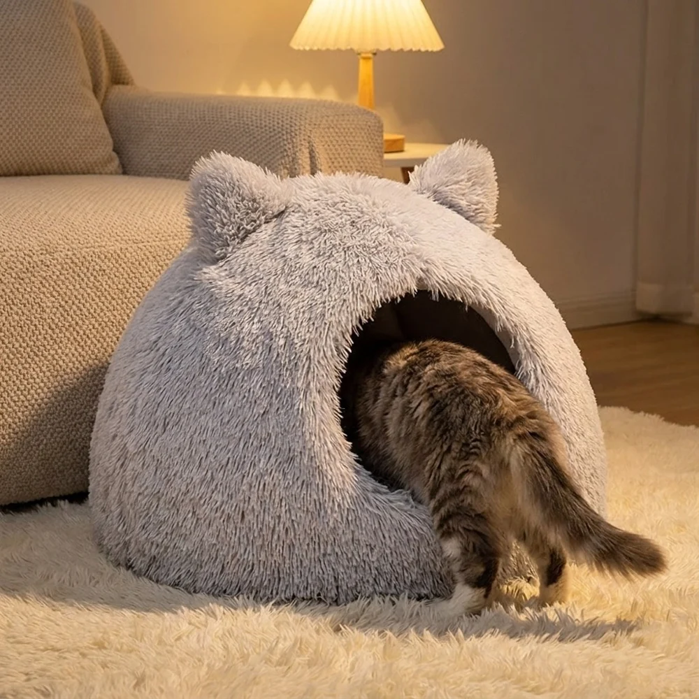 Katze steigt am Abend in die flauschige TruePet Katzenhöhle neben dem Sofa